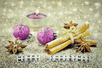 Fototapeta na wymiar Purple candle and balls on white snow. Beautiful christmas close-up decoration postcard. Cinnamon and star anise on sugar snow background. Merry Christmas writing of letters.