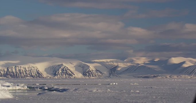 Time lapse - Clouds over snowy mountains and sea ice edge