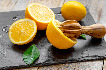 cut oranges in half and juicer on wooden background