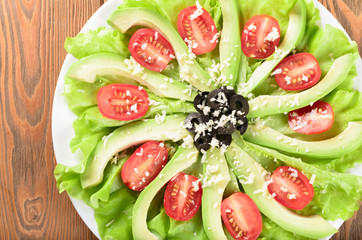 Sliced avocado with salad leaves, cherry tomatoes, olives and gr