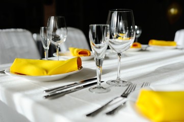 beautiful empty wine glasses and yellow napkin on a decorated table close-up.