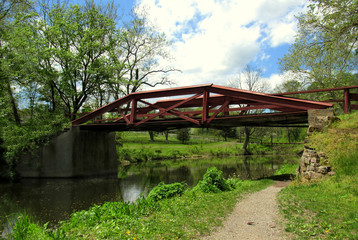 peaceful bridge over a small stream surrounded by trees and green grass