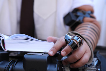 Hand with Tefillin of teenager with book of prayer. Bar Mitzvah Celebration With Tefillin