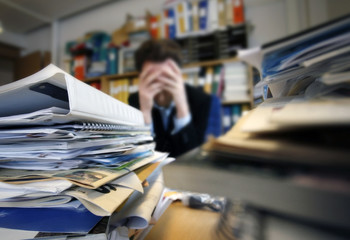 Frustrated man sitting desperate over paper work at desk