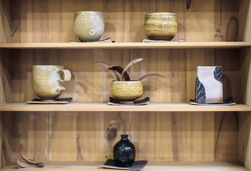 Abstract art ceramic cups and plates on wooden shelves