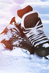 black hockey skates lying in the snow and bright sun