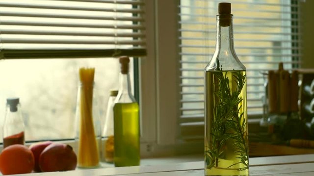 Cooking oil bottle on kitchen background. Olive oil with rosemary herb in glass bottle. Cooking ingredients. Cork bottle. Italian food products. Extra virgin olive oil