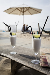 Cocktail glass with two straws and with beach landscape background