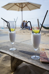 Cocktail glass with two straws and with beach landscape background