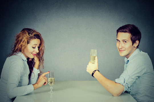 Sly man and skeptical woman sitting at table drinking wine