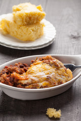 Close up of homemade baked chili in small porcelain bowl with side of cornbread