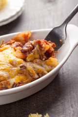 Close up of homemade baked chili in small porcelain bowl with fork