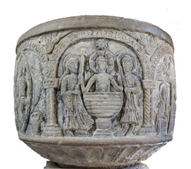 Medieval baptismal font isolated on white. A stone carving of the baptism of Jesus in a huge font