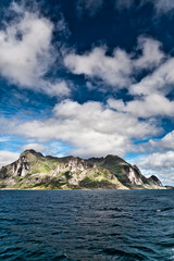 Fototapeta na wymiar Landscape of a Fjord Norway from the sea with mountain, blue sky and white clouds