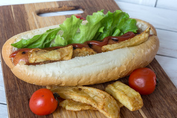 Barbecue Grilled Hot Dog with ketchup, french fries and Cherry tomatoes on wooden background