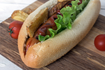 Barbecue Grilled Hot Dog with ketchup, french fries and Cherry tomatoes on wooden background