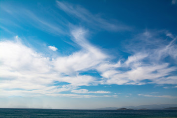 Naklejka na ściany i meble cloudy blue sky leaving for horizon above a blue surface of the sea
