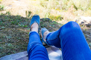 Top view female feet in jeans and sports shoes in public park