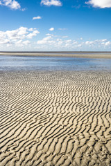 Fototapeta na wymiar Maritime landscape with blue sky white clouds and pattern in the sand, Waddenzee - Wadden Sea, Friesland, The Netherlands