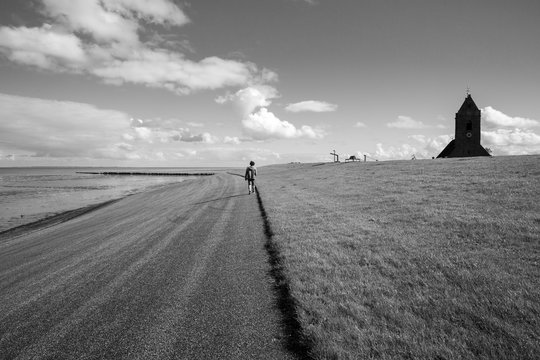 Black and white Dutch landscape with view on the dam with Old medieval church of Wierum, Friesland, The Netherlands