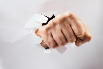 Fist punching through white paper