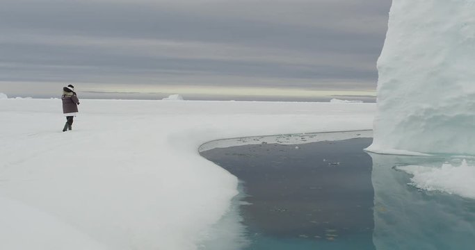Photographer walks to edge of melt pool to photo glacier cliff
