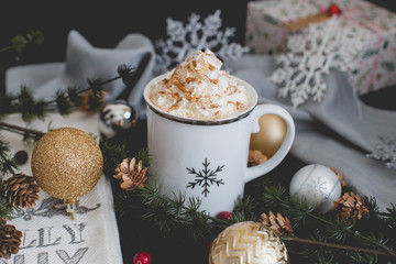Hot apple cider surrounded by silver and gold Christmas decorations and pine needles