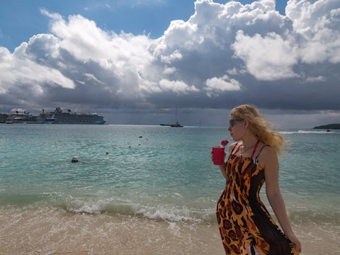 Blonde woman is enjoying her drink in the beach in great bay  in St. Maarten. 