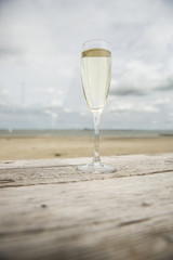 Champagne glass on a wooden table with beach background