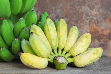 Bunch of ripe bananas and raw banana on wood background