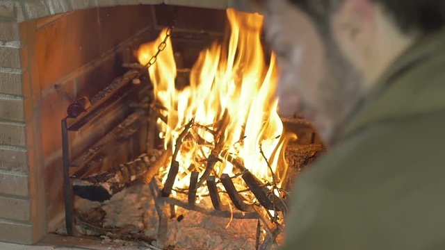 sad and mounrful guy sat in front of a fireplace