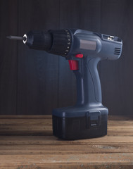 Dark blue drill on a wooden table.