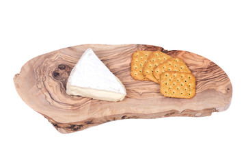 Supremely creamy soft ripened brie cheese and wheat crackers on olive wood cutting board isolated on white background