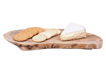 Supremely creamy soft ripened brie cheese and wheat crackers on olive wood cutting board isolated on white background