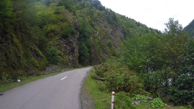 Riding on winding mountain road along fast-streamed river and steep cliffs