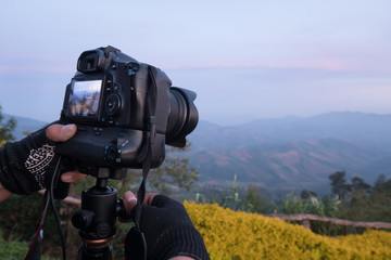 Details of professional landscape photographer adjusts dslr camera on hand.