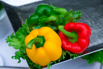 Three colored peppers on table and lettuce