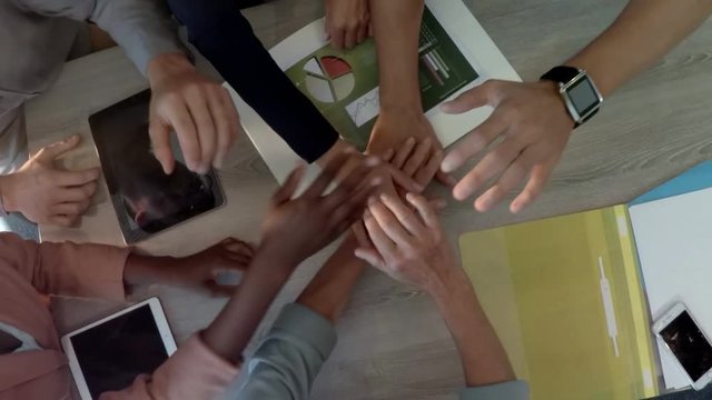 Group of business executives forming handstack on a table