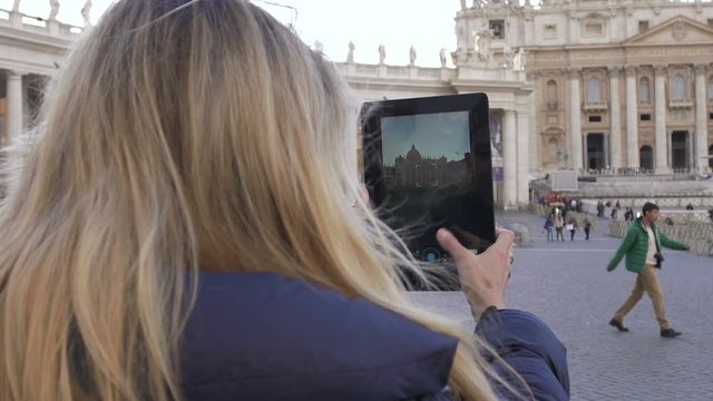 young cute woman making photos with tablet to St. Peter Church in Rome