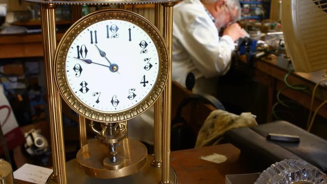 Vintage clock is on table while horologist working