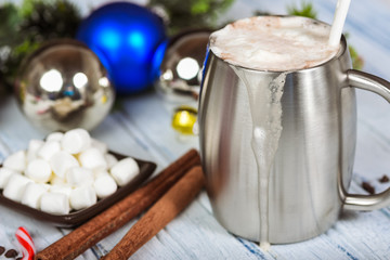Hot chocolate with frothy topping in stainless cup.   Christmas