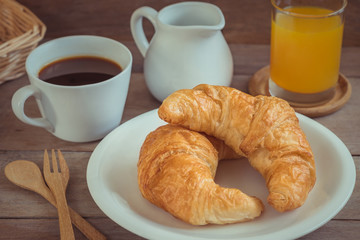 Croissants on plate with coffee cup and juice