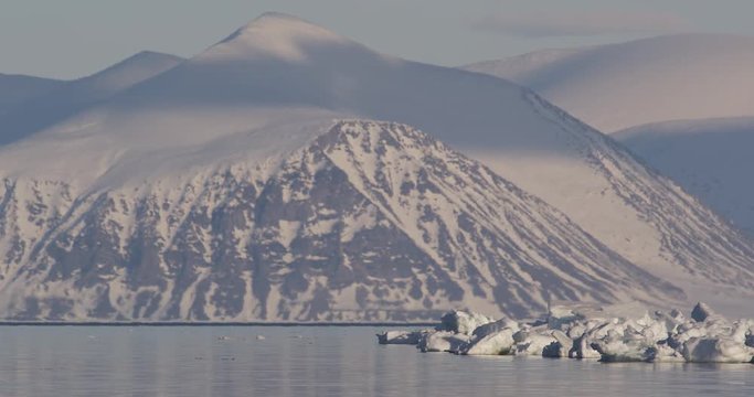 Scenic snowy mountain above icy fjord