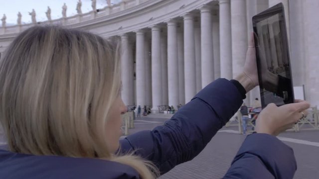 young woman is making photos to St. Peter church with tablet pc: tourism in Rome