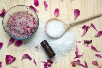 Obraz na płótnie Canvas omemade scrub for body,sea salt in wooden spoon, aroma oil, rose petals on wooden background. Spa concept.