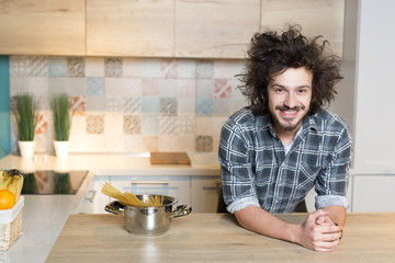 Fototapeta na wymiar Handsome young man in plaid shirt standing in the kitchen