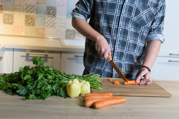Smiling young man chopping vegetables in the kitchen at home