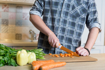 Smiling young man chopping vegetables in the kitchen at home