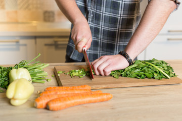 cooking, food and home concept - close up of male hand cutting v