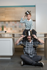 Father and son having fun in kitchen playing with pots